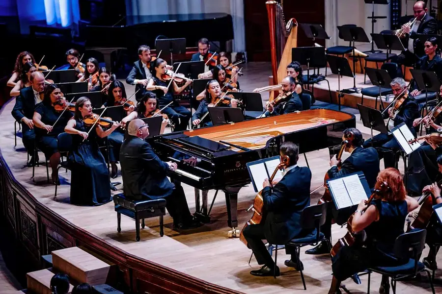 Stessa scena del concerto per pianoforte e orchestra, inquadratura leggermente piu' stretta e piu' scura ai bordi, con il violoncellista di spalle in primo piano.